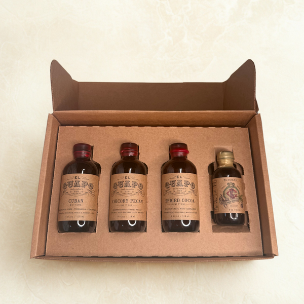 Four bottles of El Guapo Bitters in a brown craft shipping mailer