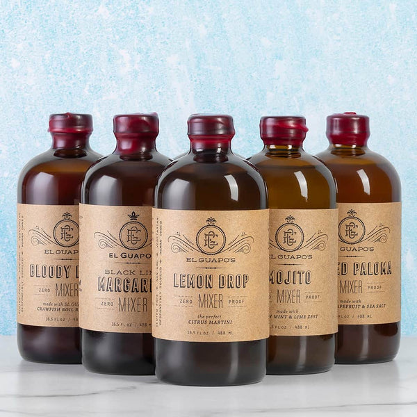 Five full-size bottles of assorted El Guapo mixers on a light blue background