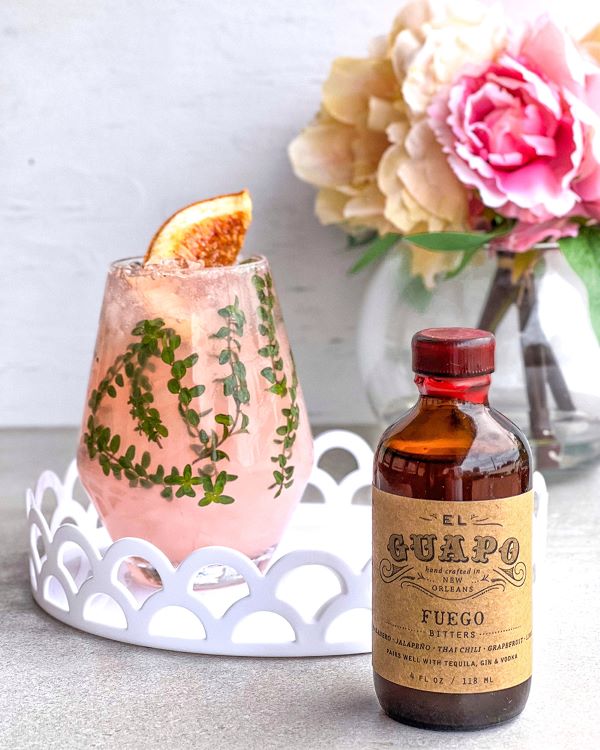 El Guapo Fuego spicy cocktail bitters bottle with pink drink.
