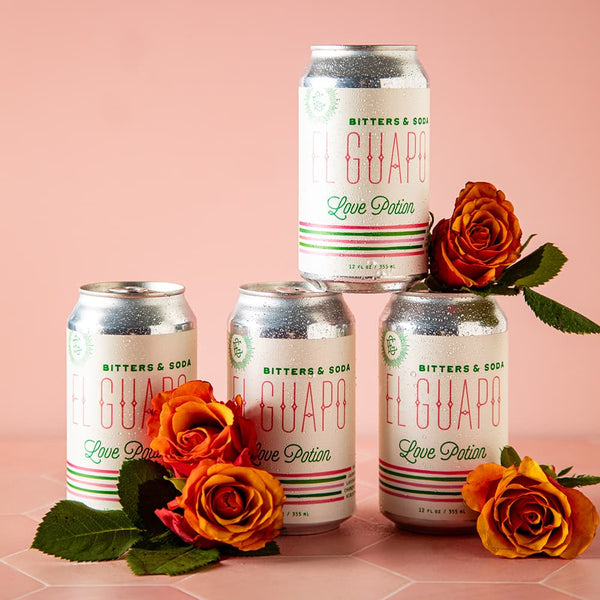 Four cans of El Guapo Love Potion Bitters & Soda on a pink background with roses.