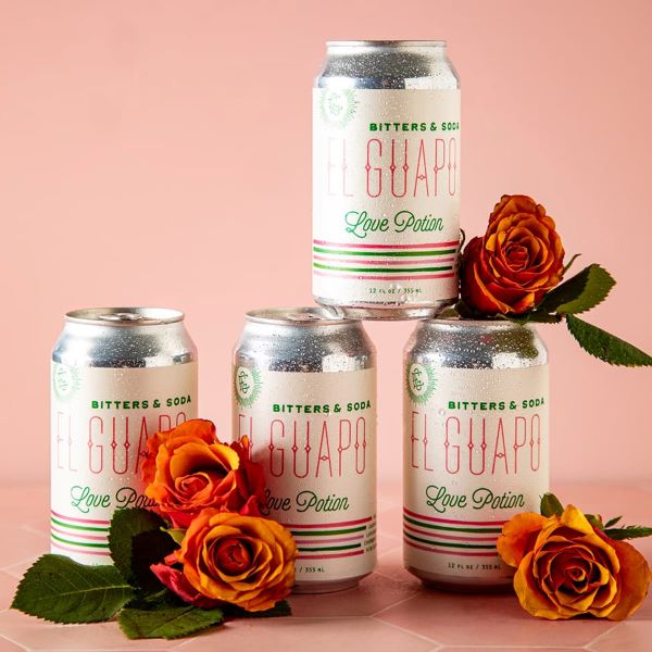 Four cans of El Guapo Love Potion Bitters & Soda styled with orange roses.