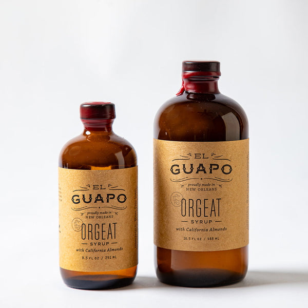 Size comparison of two bottles of El Guapo orgeat on white background