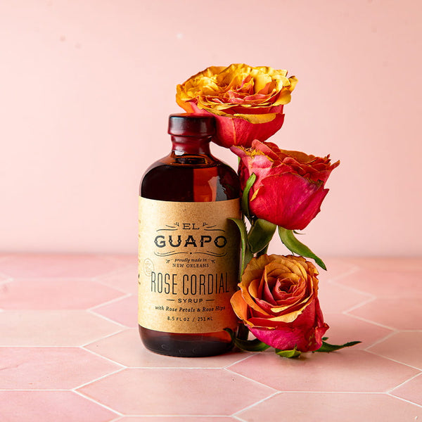 8.5 oz Bottle of El Guapo Rose Cordial syrup with roses on a pink background
