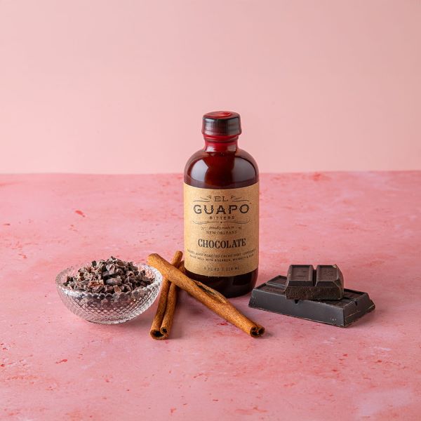 Bottle of El Guapo Chocolate Bitters displayed with dark chocolate and cinnamon