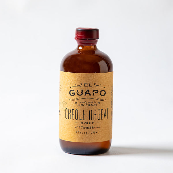 Small glass bottle of Creole Orgeat syrup with a brown label on a white background