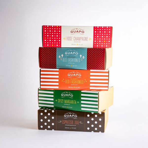 A variety of stacked El Guapo cocktail kit gift boxes.