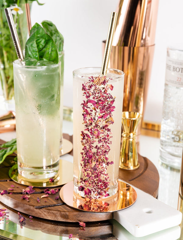 Lillet Blanc cocktails in highball glasses decorated with dried rose petals on a wooden tray