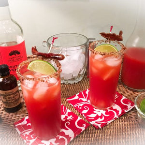 Spicy Bloody Southern Caesar cocktails with bacon next to El Guapo Gumbo Bitters
