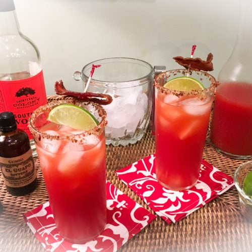 Spicy Bloody Southern Caesar cocktails with bacon next to El Guapo Gumbo Bitters