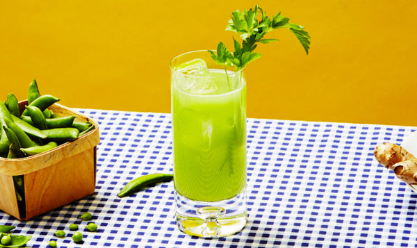 Peas & Cues green cocktail with a basket of sugar snap peas on a blue checkered tablecloth