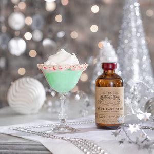 Green El Guapo Grasshopper cocktail with a crushed candy cane rim next to Candy Cane Syrup