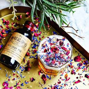 Sweet Potato Pie Old Fashioned with edible flower petals next to Holiday Pie Bitters