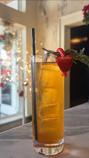Red Nose Punch rum cocktail with a candy cane, strawberry, and rosemary garnish