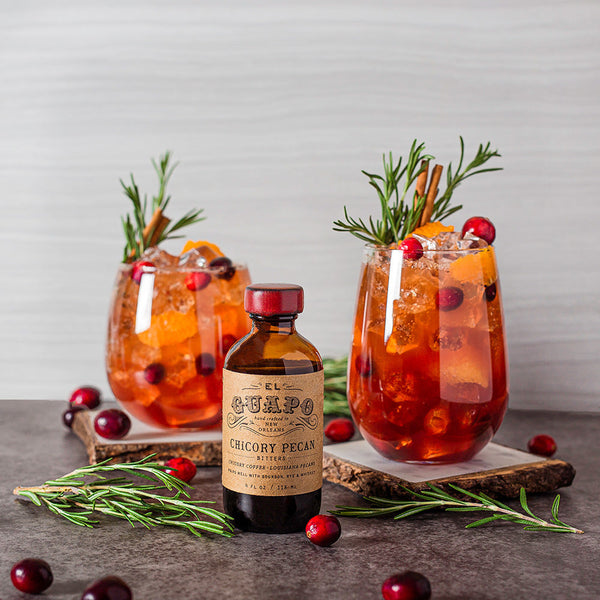 Thanksgiving cocktails garnished with rosemary next to El Guapo Chicory Pecan Bitters