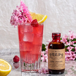 Raspberry Beret cocktail with lemon and raspberry next to Love Potion Bitters
