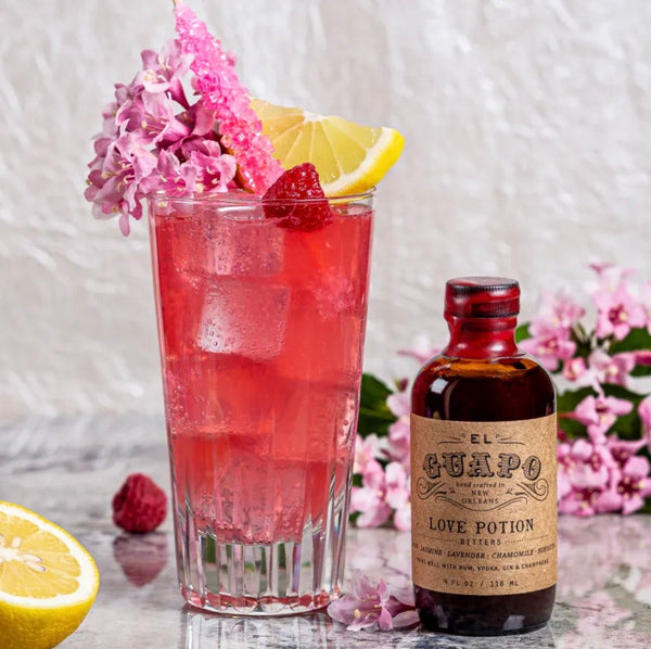 Raspberry Beret cocktail with lemon and raspberry next to Love Potion Bitters