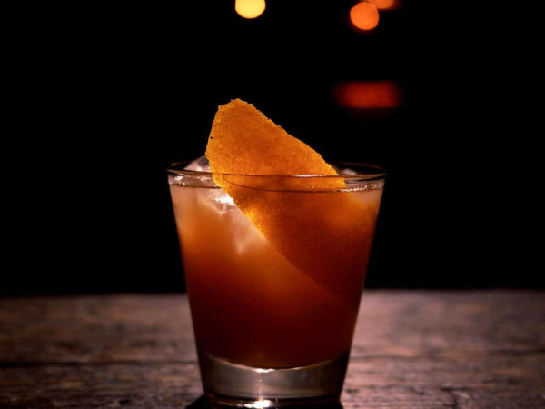 Classic Old Fashioned cocktail garnished with a large orange peel twistv