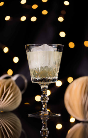 Clarified Holiday Eggnog Punch in a crystal coupe glass with warm festive bokeh lights
