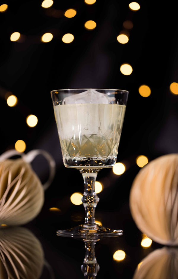 Clarified Holiday Eggnog Punch in a crystal coupe glass with warm festive bokeh lights
