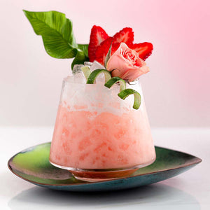 Coconut Rose Margarita garnished with a pink rose, strawberries, and a lime twist