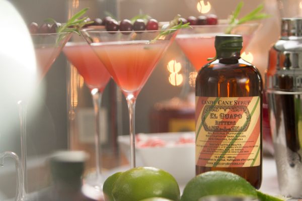 El Guapo Candy Cane Syrup bottle next to festive holiday cocktails