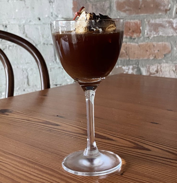 Neutral Ground Side chicory liqueur cocktail with a toasted marshmallow garnish on a wooden table