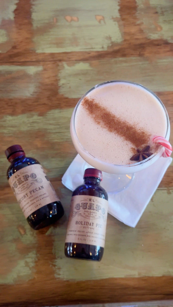 Spiced Chai Martini with star anise garnish next to El Guapo holiday bitters bottles