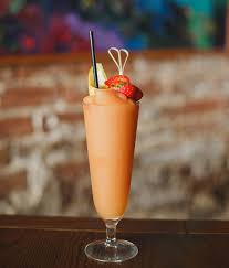The Rose Tattoo frozen strawberry daiquiri in a tall glass with a decorative garnish