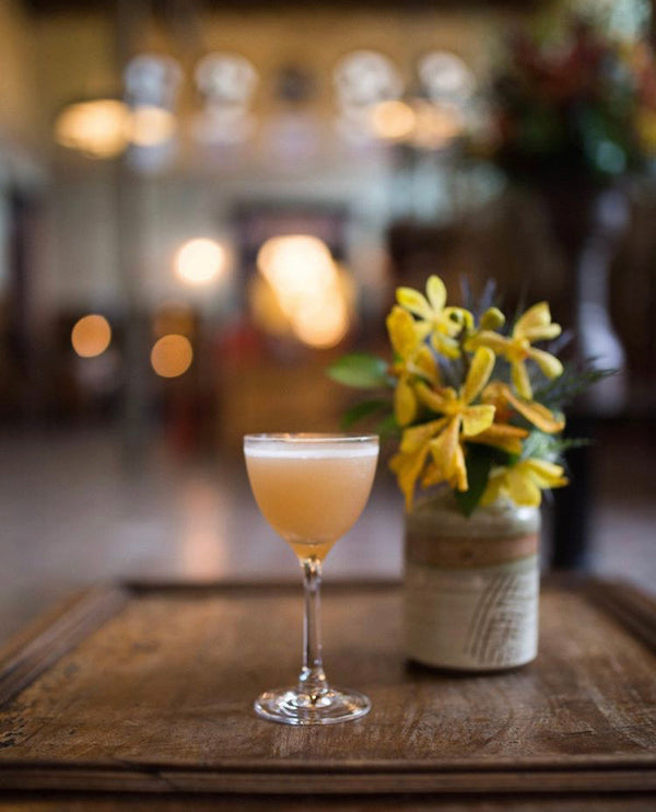 Three Emmas sherry and gin cocktail on a wooden tray next to yellow flowers