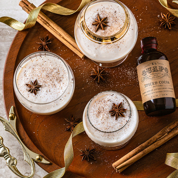 Three Brandy Milk Punch cocktails with star anise garnishes next to Spiced Cocoa Bitters