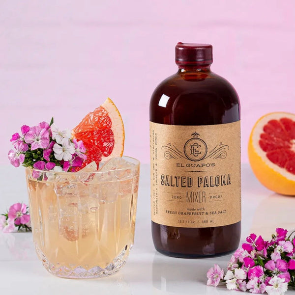 Salted Paloma cocktail with grapefruit and flowers next to El Guapo Salted Paloma Mixer