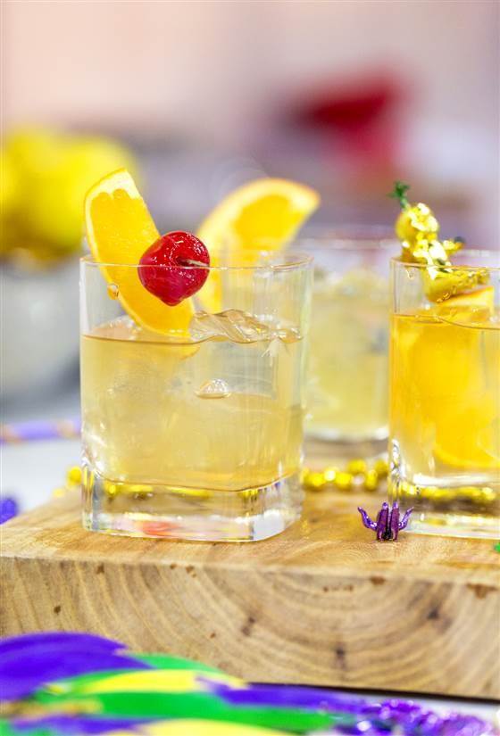 Tequila Old Fashioned cocktail with a cherry and orange garnish on a wooden block
