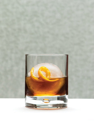 Evangeline Stirred bourbon cocktail with an ice sphere and orange twist garnish