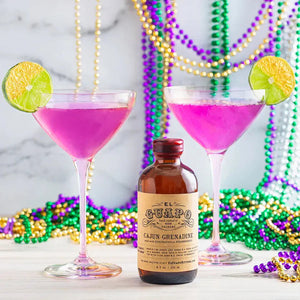 French Quarter 75 pink cocktails next to a bottle of El Guapo Cajun Grenadine