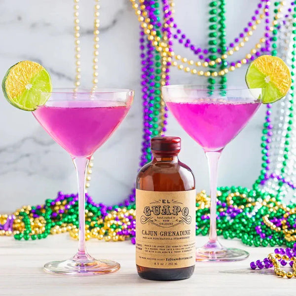 French Quarter 75 pink cocktails next to a bottle of El Guapo Cajun Grenadine