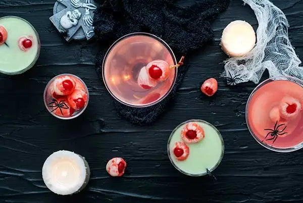 Spooky Halloween cocktails garnished with lychee eyeballs on a dark background