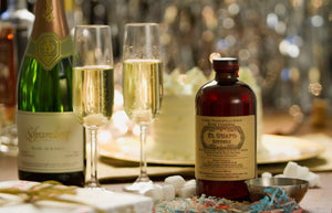 Champagne glasses and bottle next to El Guapo Holiday Pie Bitters