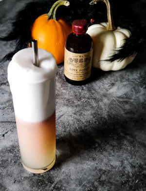 Haunted Estate Fizz cocktail with thick foam, pumpkins, and El Guapo Love Potion Bitters