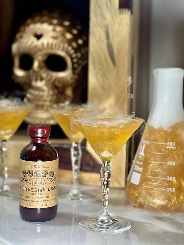 Hocus Pocus glitter cocktail with dry ice next to a bottle of El Guapo Polynesian Kiss Bitters