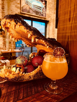 Gator’s Breath tiki drink with a dried lime wheel next to an alligator head decoration