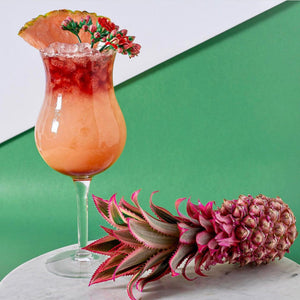Stop, You're Making Me Blush tropical cocktail garnished with a pink pineapple slice