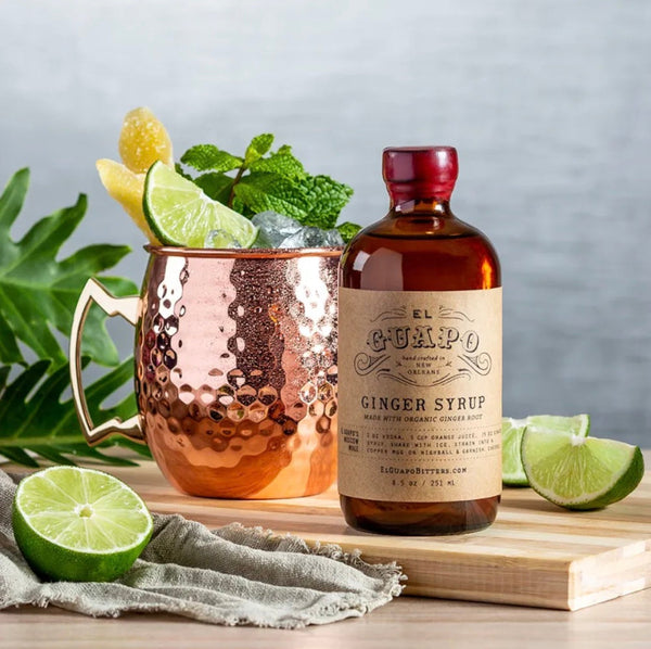 Moscow Mule cocktail in a copper mug next to a bottle of El Guapo Ginger Syrup