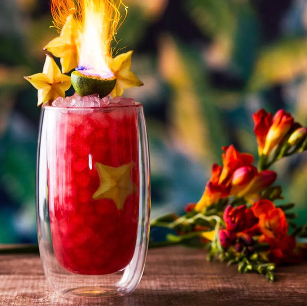 Powder Keg red rum and Campari cocktail with starfruit and a flaming lime garnish