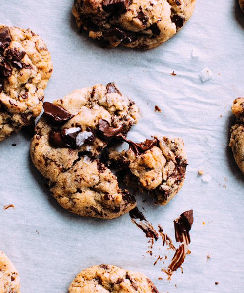 Freshly baked chocolate chip cookie broken in half with melted chocolate and sea salt