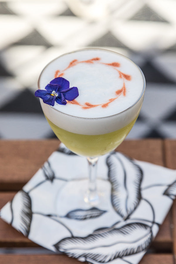 Cool Hand Cuke cocktail with foam art and a purple edible flower garnish