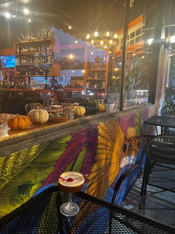 Santa's Tipple cocktail on an outdoor patio table next to a colorful painted mural