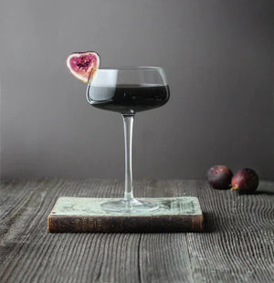 Dark fig cocktail in a coupe glass on a vintage book