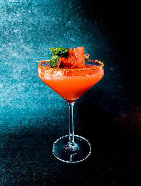 Watermelon Mezcalrita cocktail in a coupe glass with a chili powder rim and mint garnish