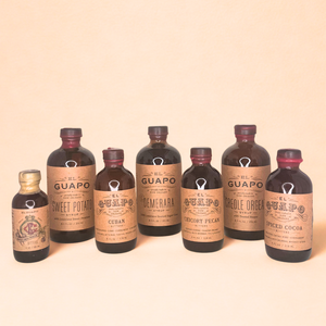 Collection of 4 bitters and 3 syrups for bourbon pairings on a butter yellow background