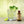 Mojito cocktail with lime wedges and mint leaves next to a bottle of Single Serving El Guapo Mojito Mixer on a coaster atop a wooden surface.